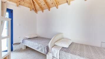Un dormitorio con dos camas individuales, techo de madera y pared blanca.