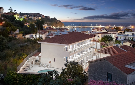 A coastal town with a prominent white building featuring balconies and a swimming pool.