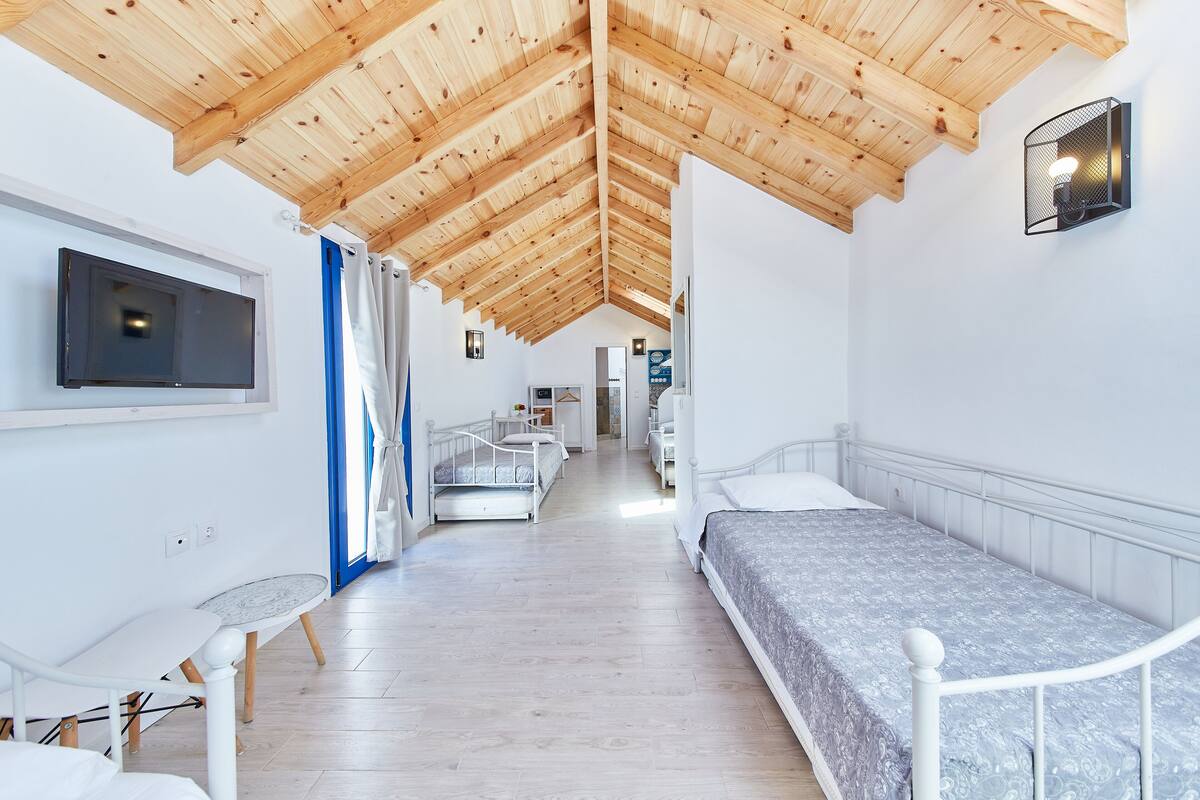 A modern room with a wooden ceiling, a bed, a TV, and a small table.