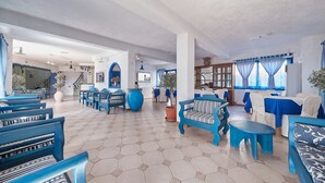 A spacious lobby with blue and white furniture, a tiled floor, and a staircase in the background. - Atheras (Ikaria)