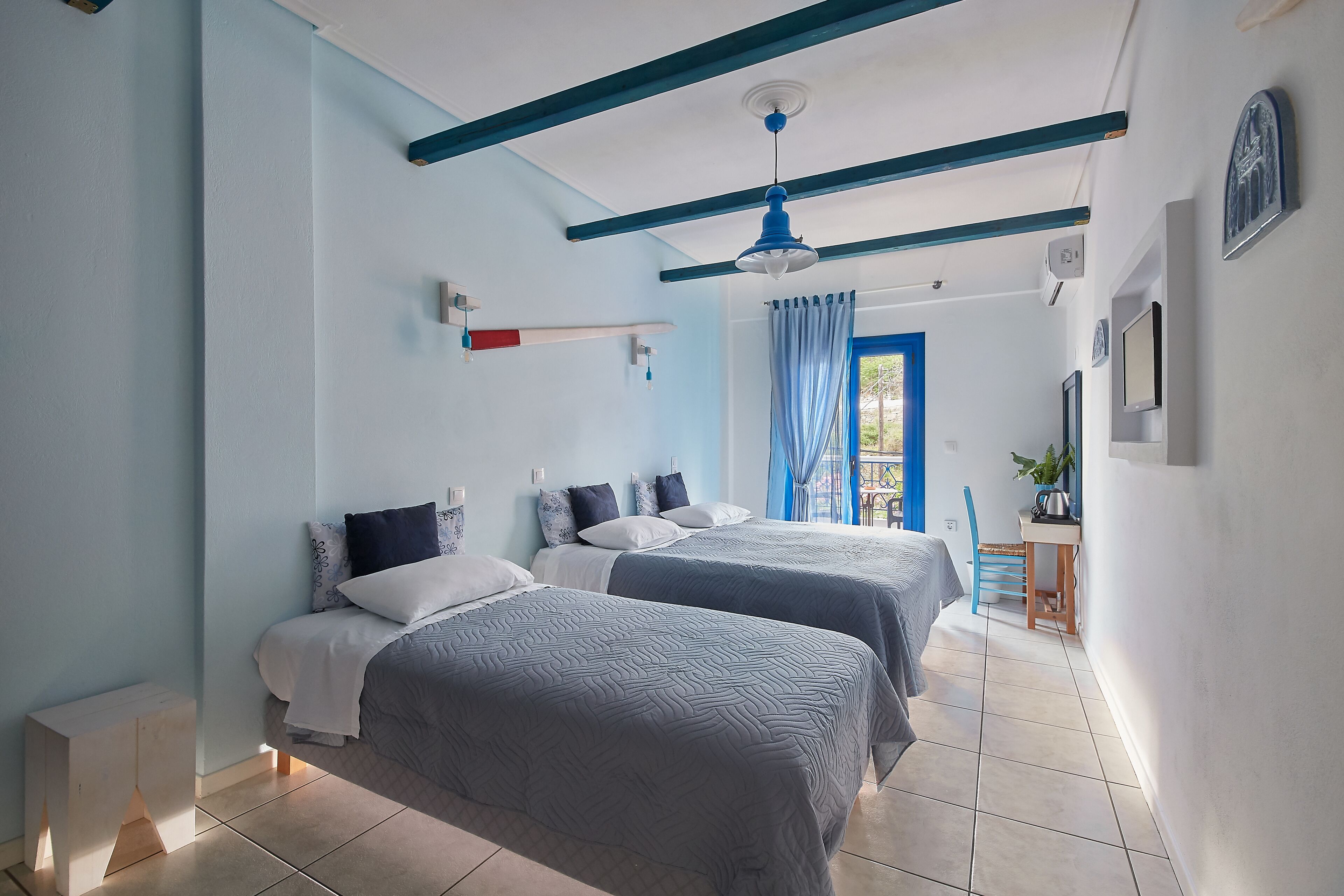 Una camera da letto con due letti, un ventilatore a soffitto e una scrivania piccola con una sedia.
