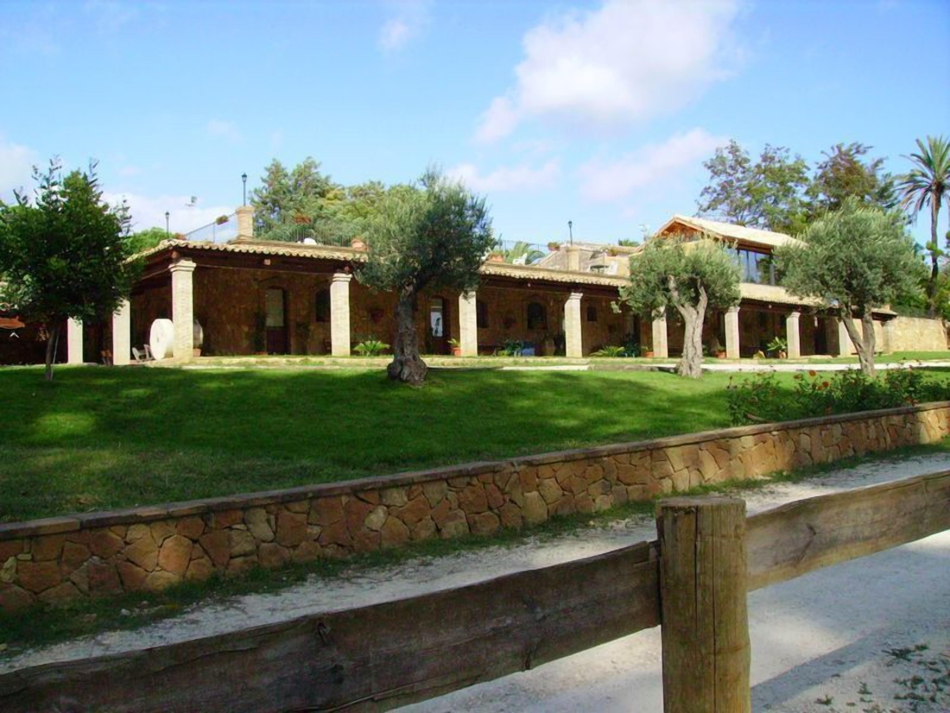 A traditional Mediterranean-style building with a stone facade, multiple rooms, and a well-maintained lawn.