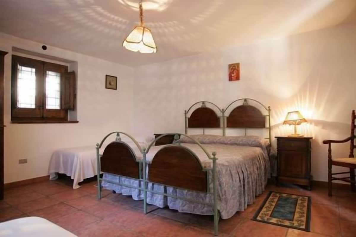 Un dormitorio con dos camas, una ventana, una lámpara y una silla.