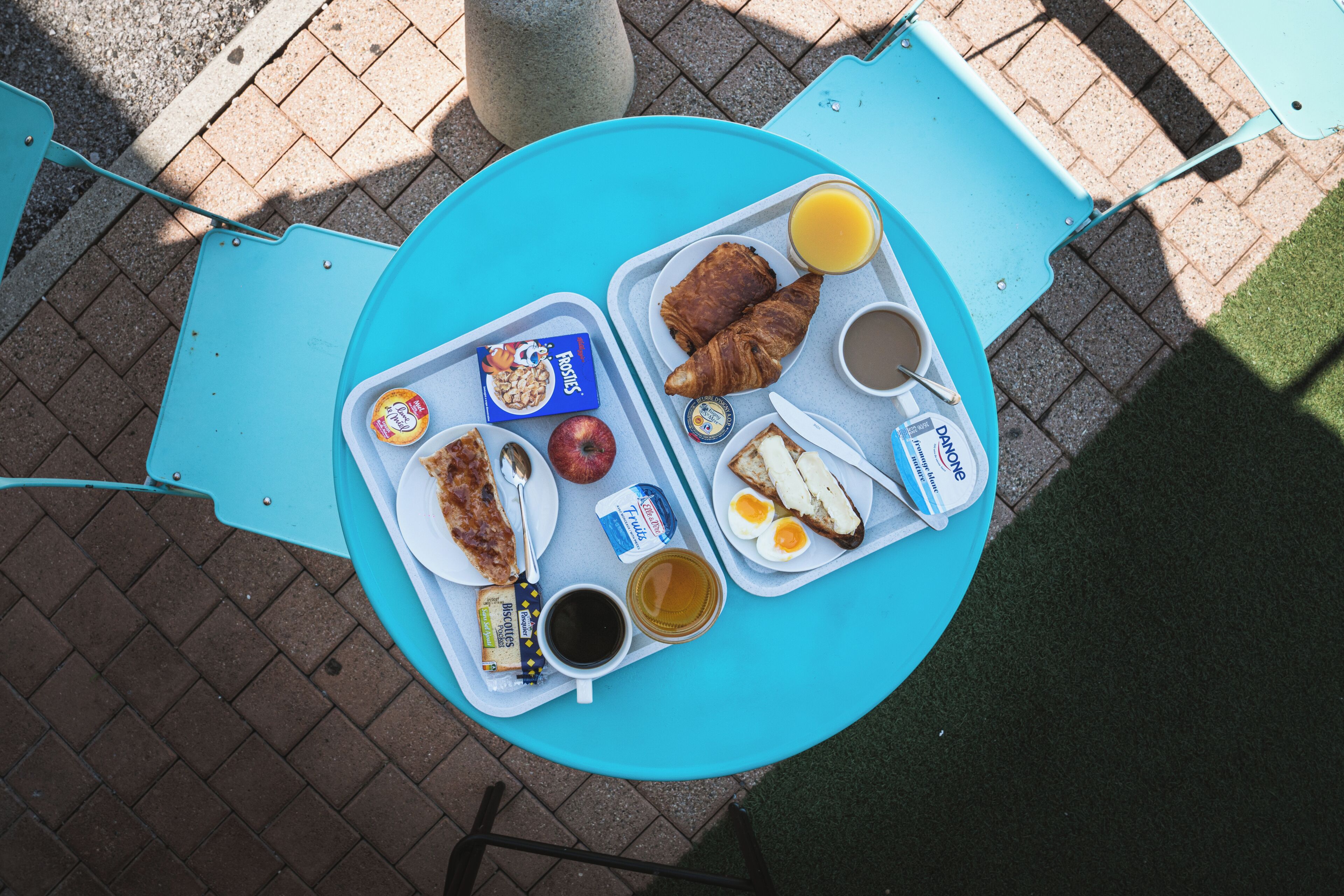 Una mesa con alimentos para el desayuno, como cruasanes, huevos, jugo y café.