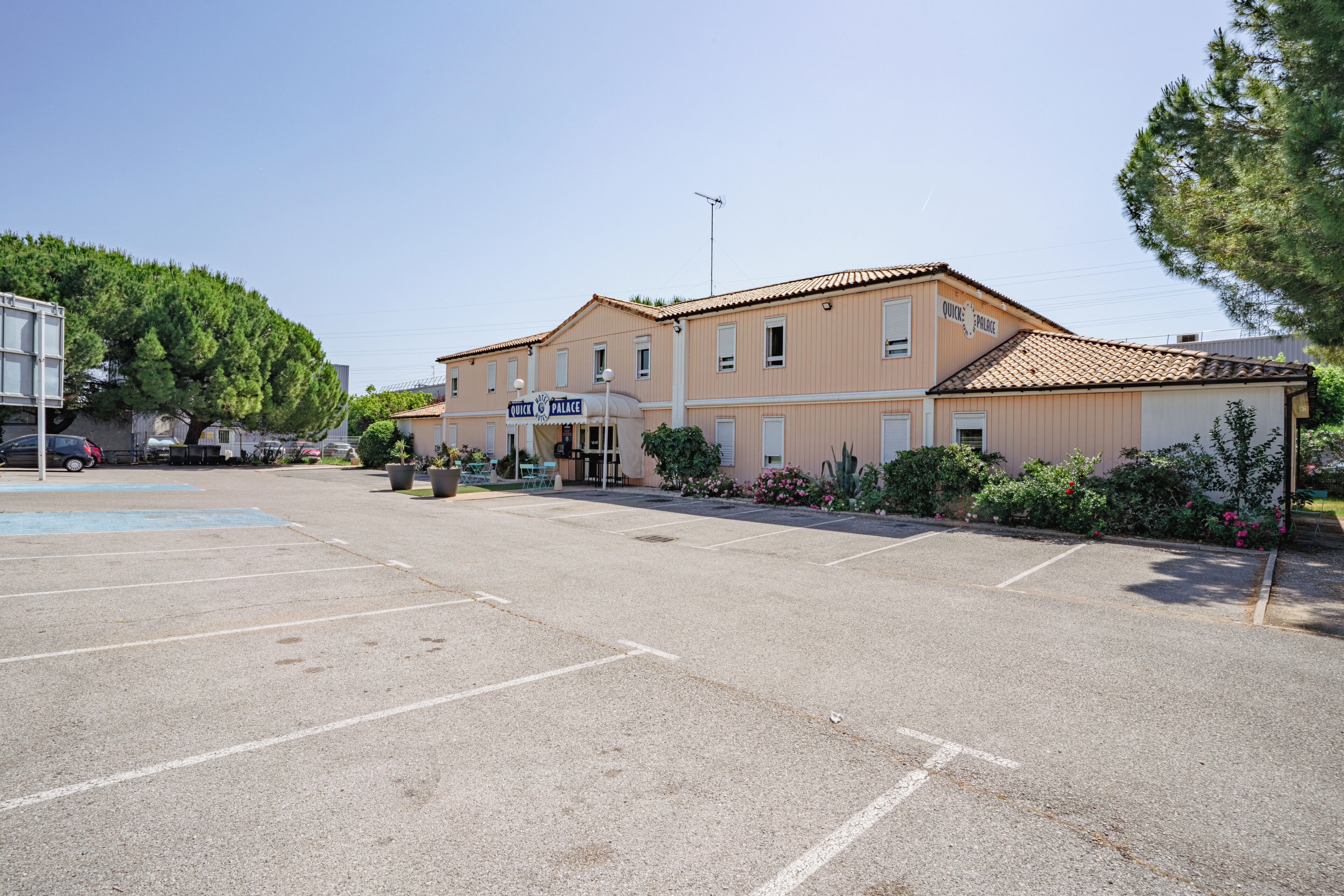 A building with a sign reading 'Quick Palace' and a parking lot in front.