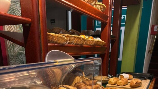 Un bufé de desayuno con diversas opciones de comida, incluyendo bollería, pan y productos lácteos.