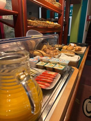 Un bufé de desayuno con diversas opciones de comida, incluyendo bollería, pan y productos lácteos.