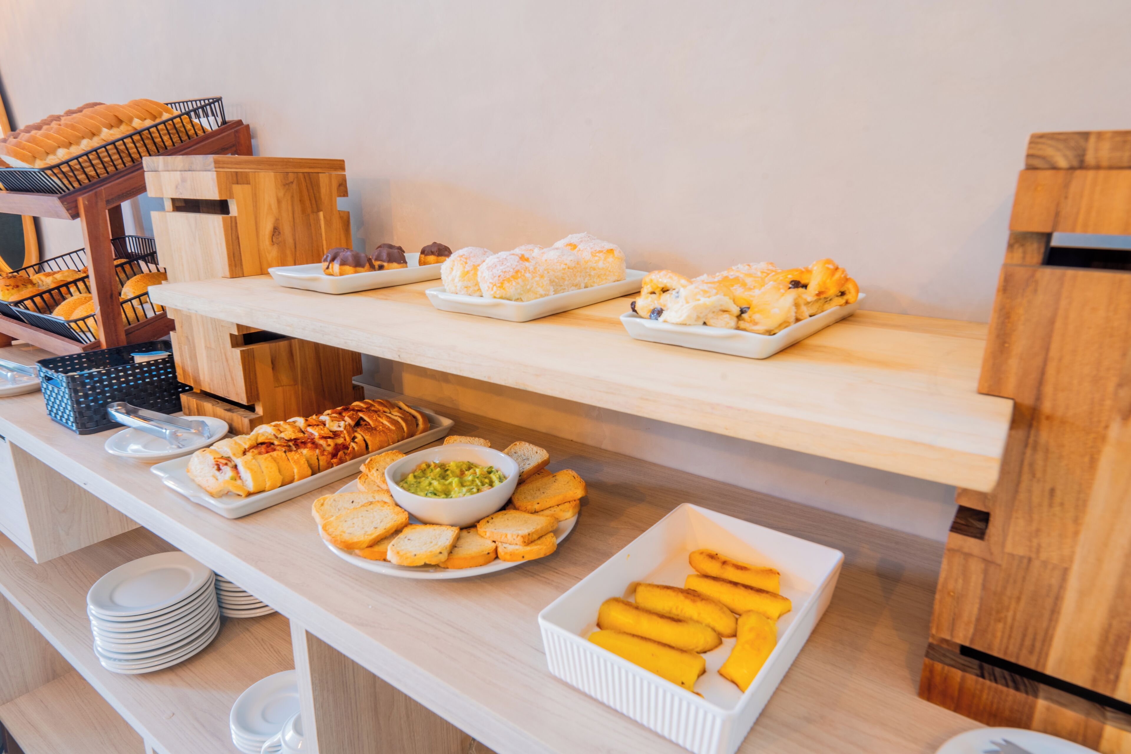 Een buffet met diverse gerechten, waaronder brood, gebak en een schaal guacamole.