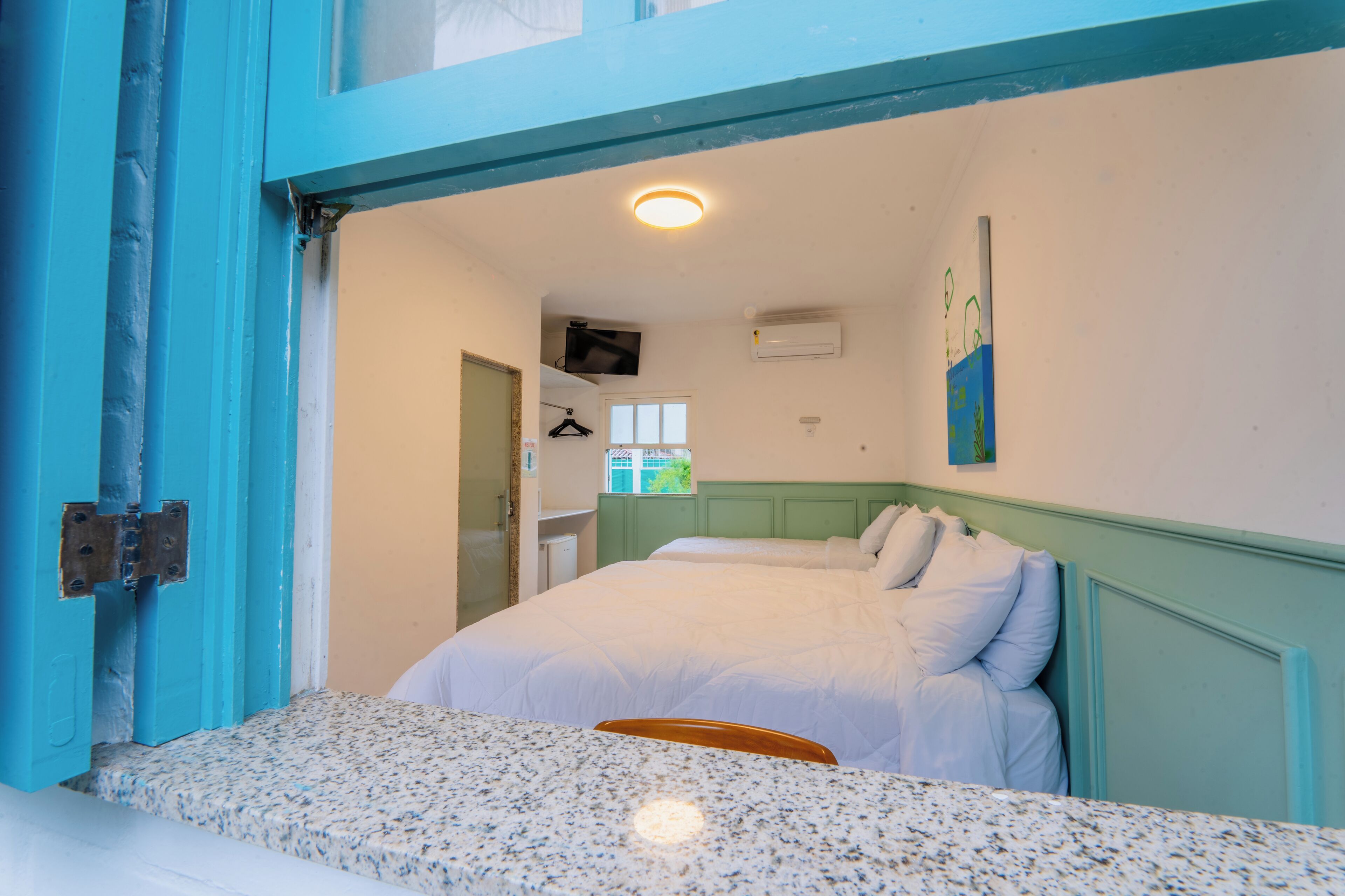 Una habitación con dos camas, televisión y ventana.
