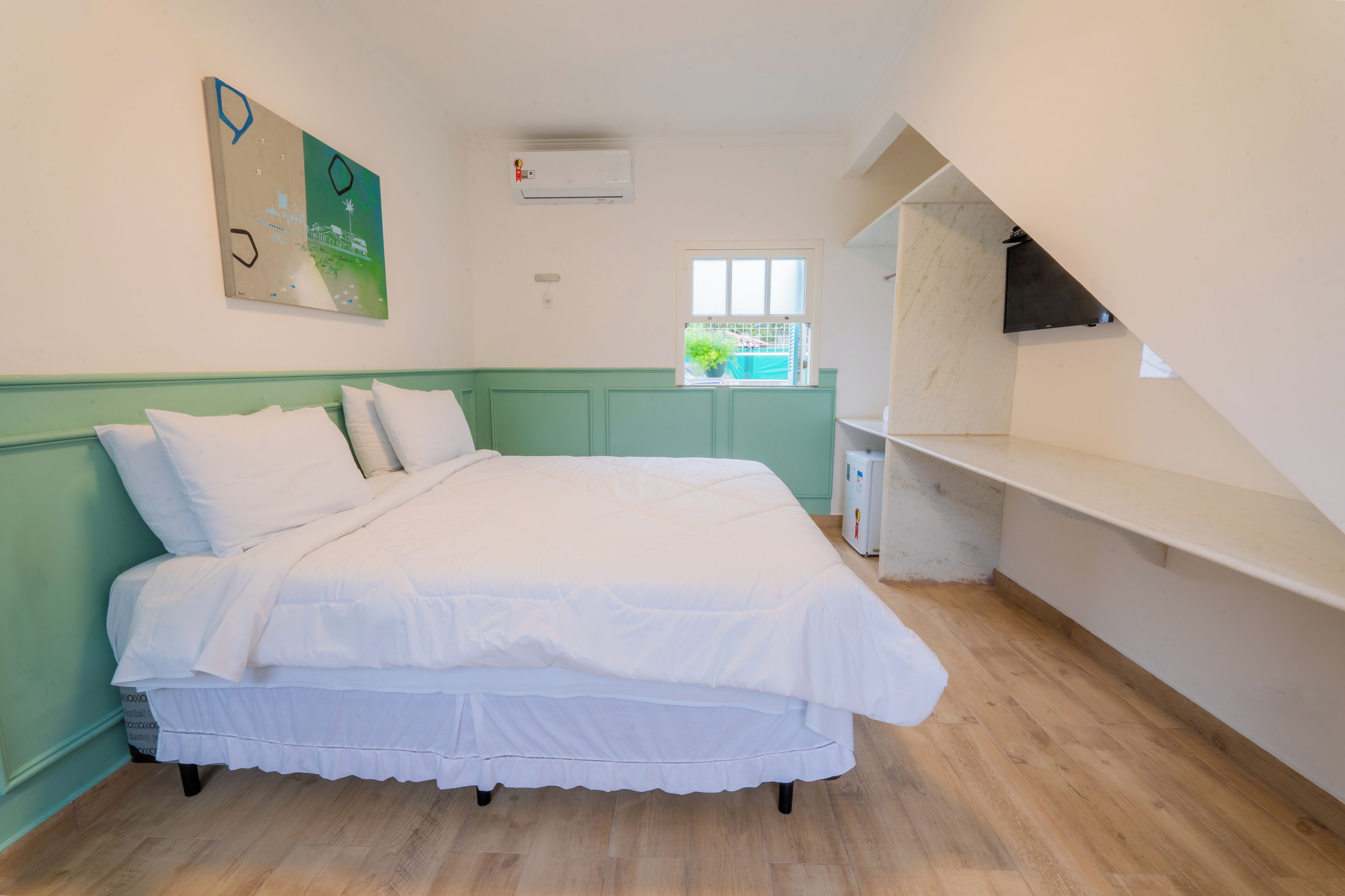 A bedroom with a bed, a window with a view, and a small balcony.