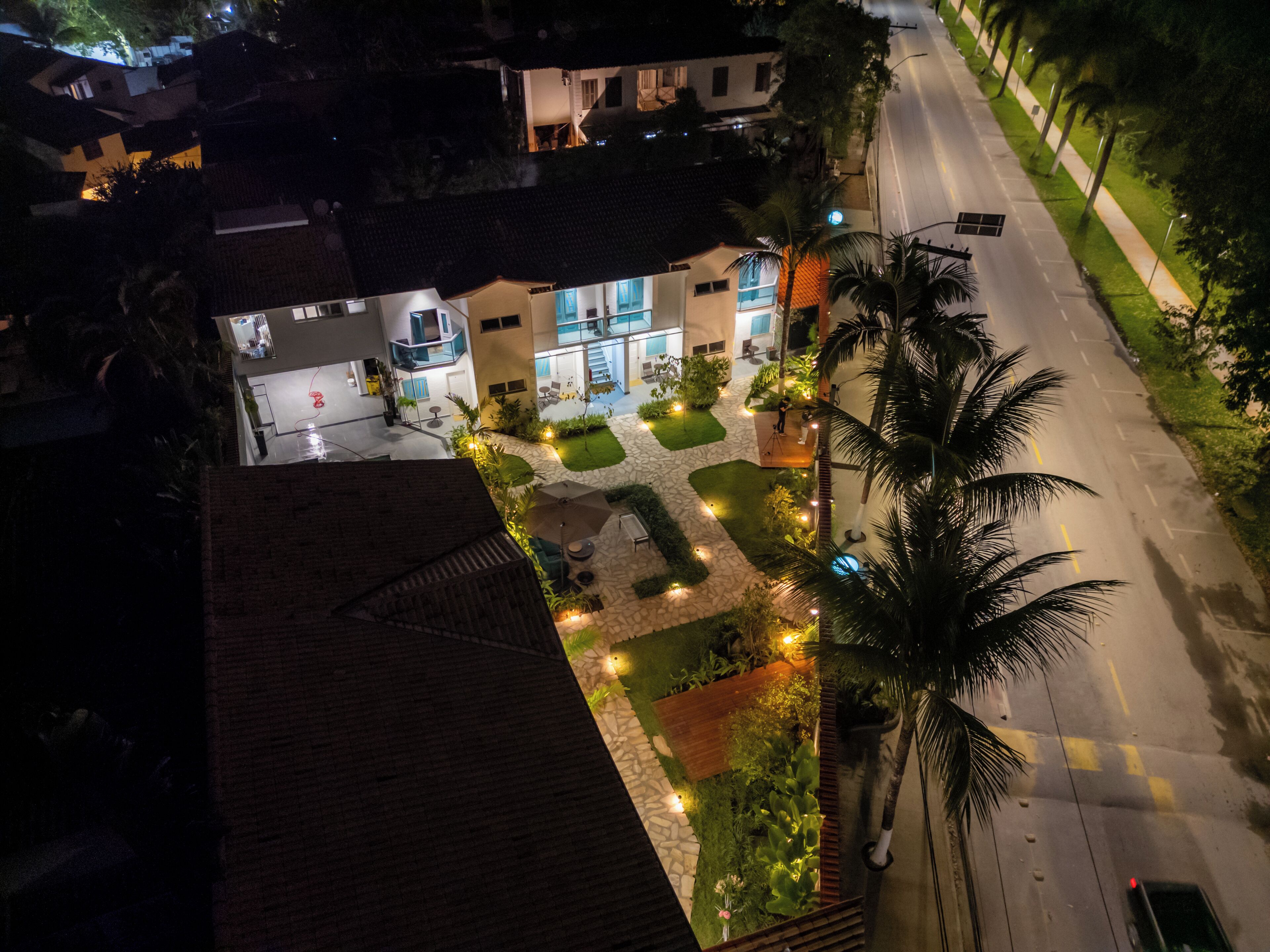 An aerial view of a hotel courtyard with a paved area, palm trees, and a well-lit entrance.