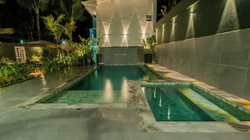 Una piscina al aire libre, sombrillas, sillones reclinables de piscina