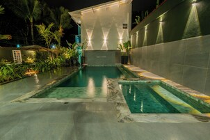 Una piscina al aire libre, sombrillas, sillones reclinables de piscina