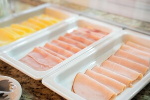 Een buffet met netjes gepresenteerde plakjes ham en kaas.