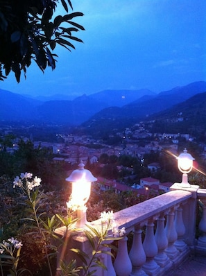 A balcony with a view of a town and mountains at dusk. - Auberge Provencale (Sospel)