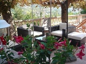 An outdoor seating area with wicker furniture and a view of greenery. - Auberge Provencale (Sospel)