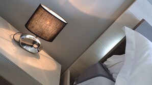 A hotel room with a bed, a bedside table with a lamp, and a wall-mounted light fixture. - Auberge Provencale (Sospel)