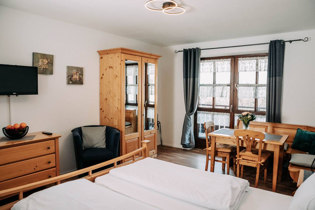 A hotel room with a bed, a desk, a chair, a wardrobe, and a television.