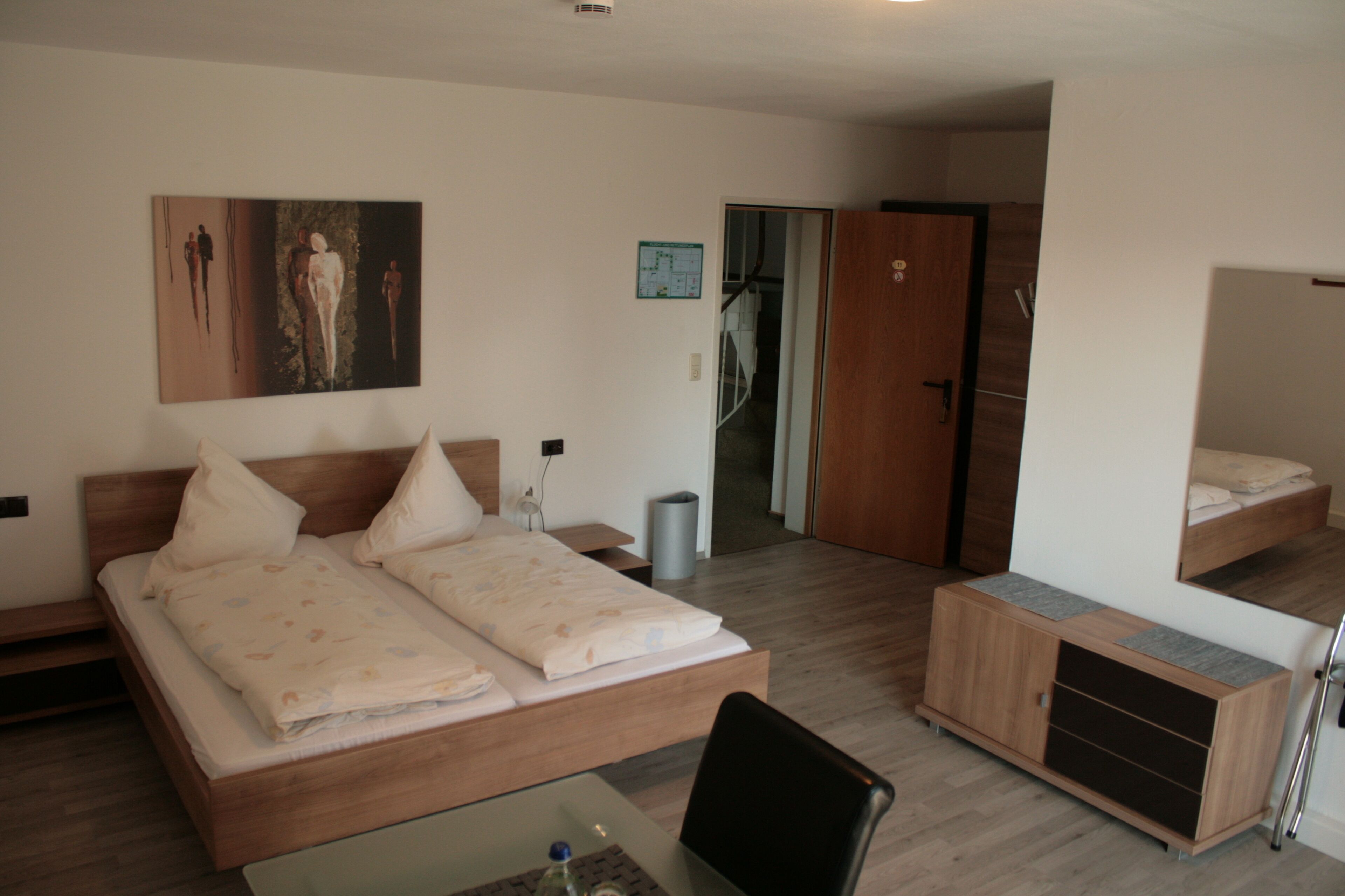 Een moderne hotelkamer met een groot bed, een bureau en een garderobe.
