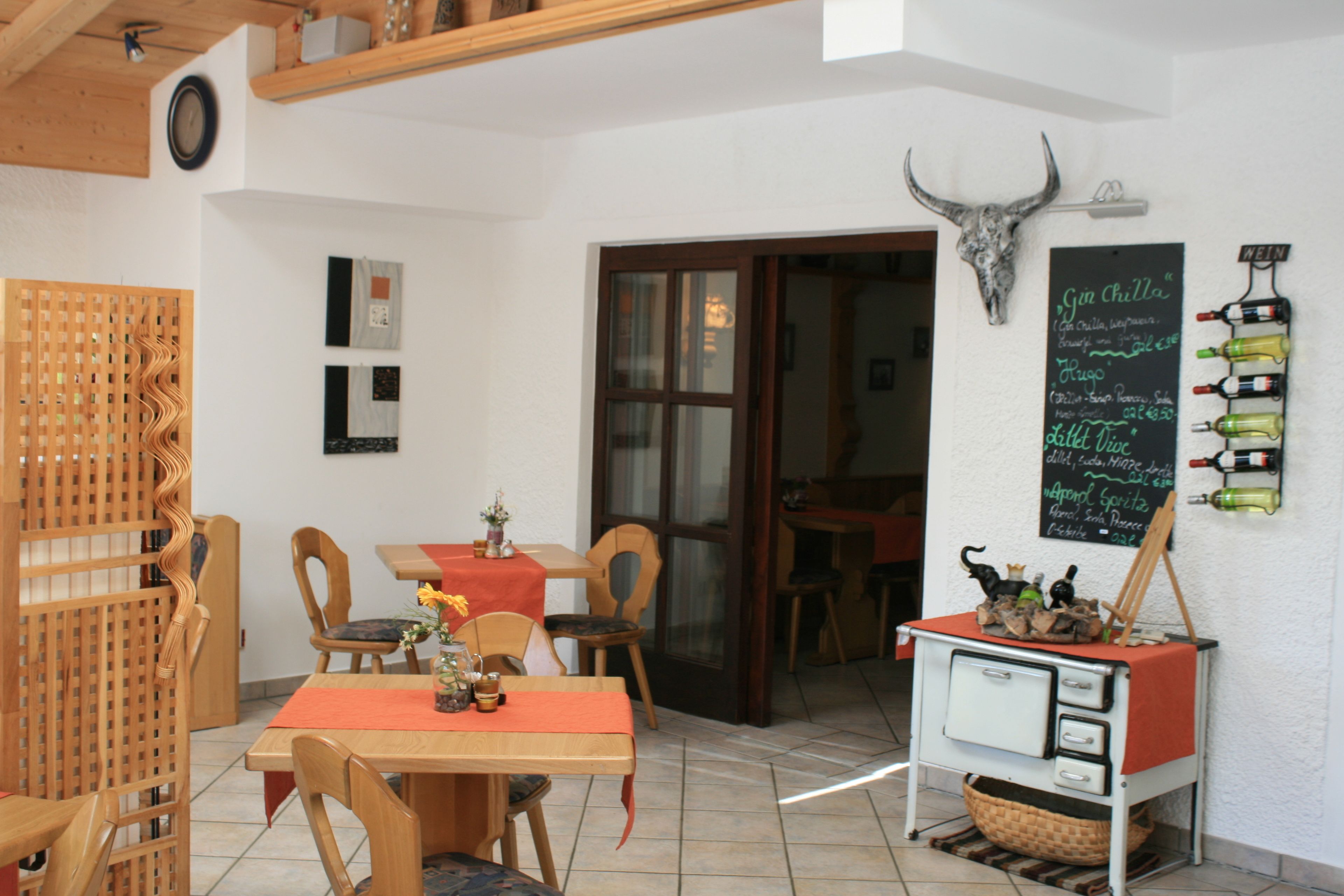 Un comedor con muebles de madera, un menú en pizarra y una estantería para vinos.