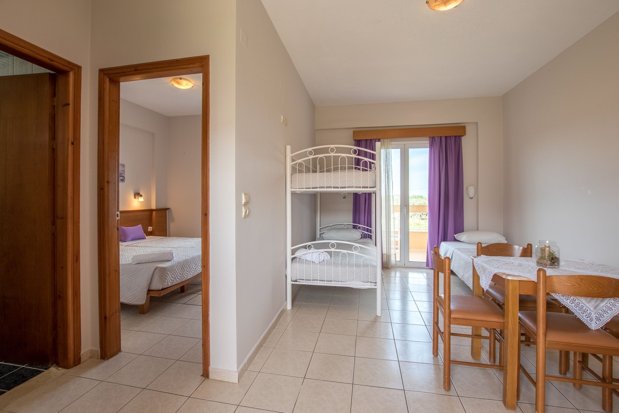 Een kamer met stapelbedden, een eettafel met stoelen en uitzicht op buiten.