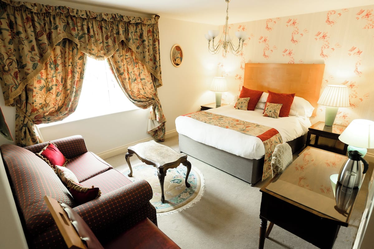 A hotel room with a bed, a sofa, a coffee table, and a nightstand.