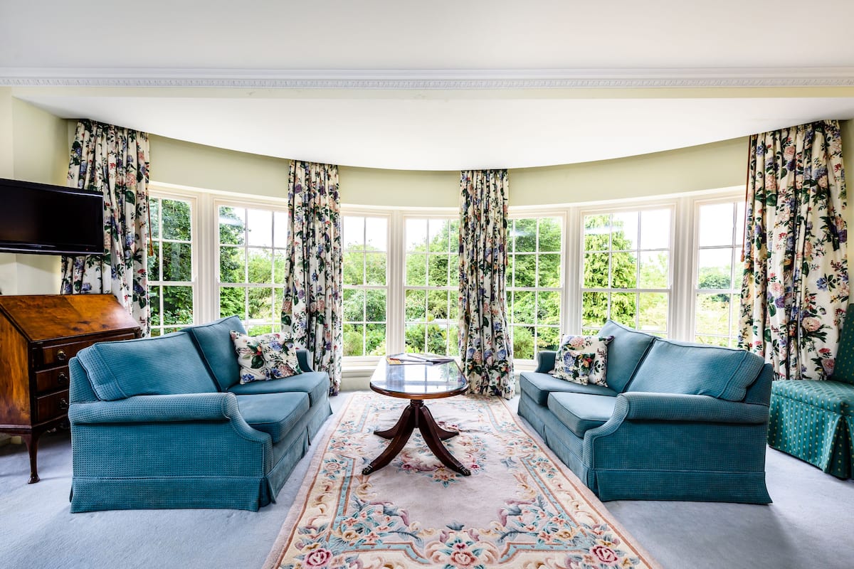 A room with two blue sofas, a wooden coffee table, and a TV mounted on the wall.