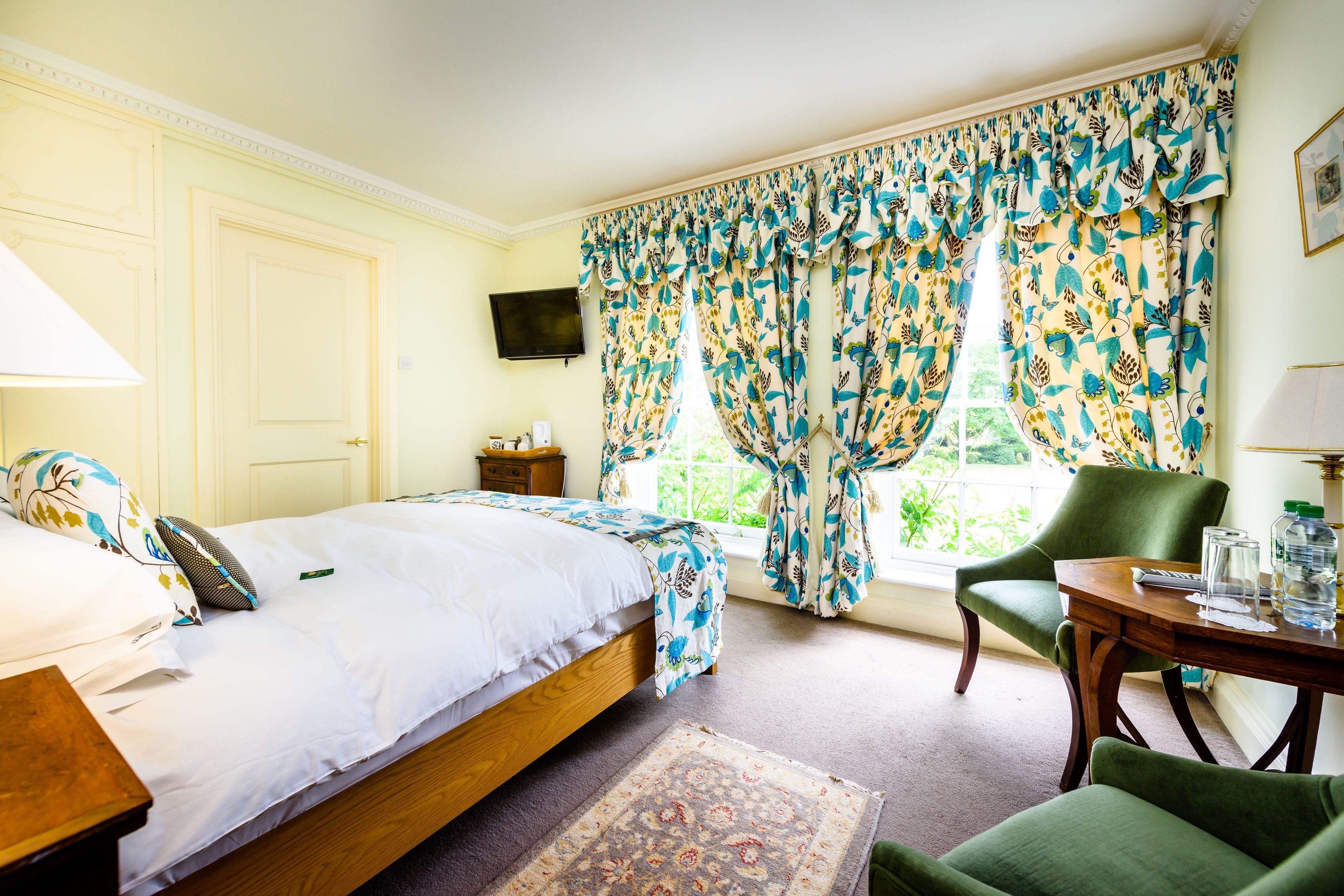 A bedroom with a bed, a chair, a table, and curtains.