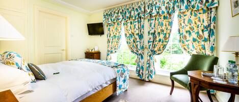 A bedroom with a bed, a chair, a table, and curtains.