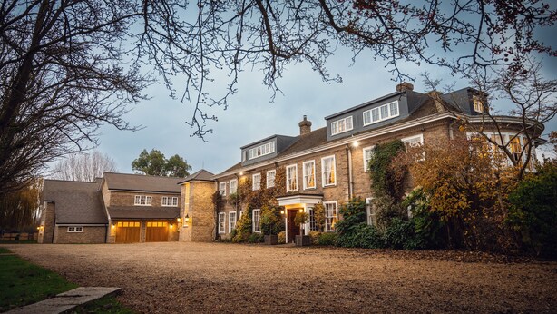 A large, multi-story brick house with a driveway leading to a gated entrance. - Rectory Farm (Cambridge)