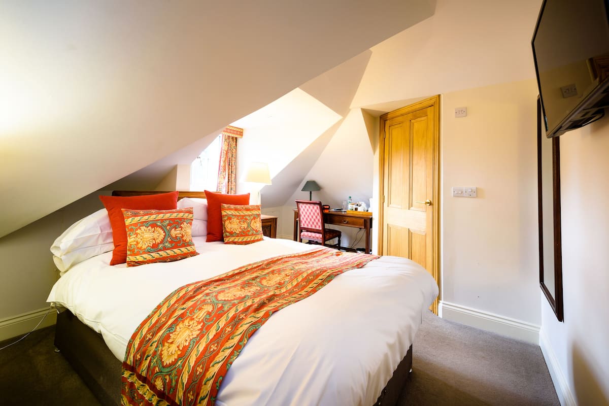 A bedroom with a large bed, a desk, and a chair.