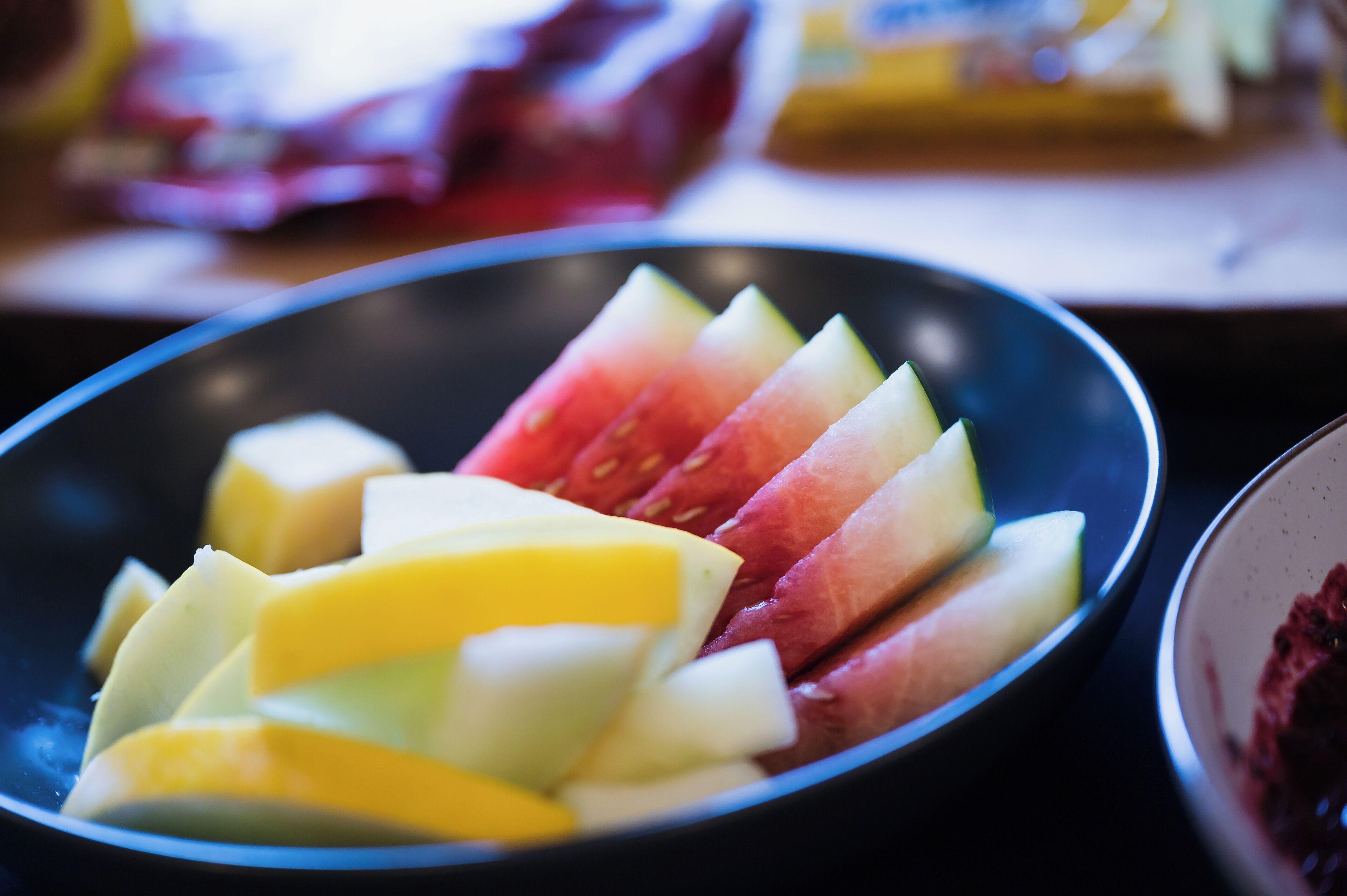 En skål med skivad frukt, inklusive äpplen och mango.