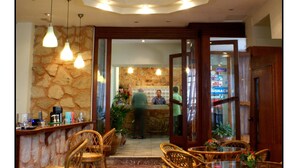 A dining area with wicker chairs and tables, a stone wall, and a bar counter. - Hotel Krystal (Sitia)