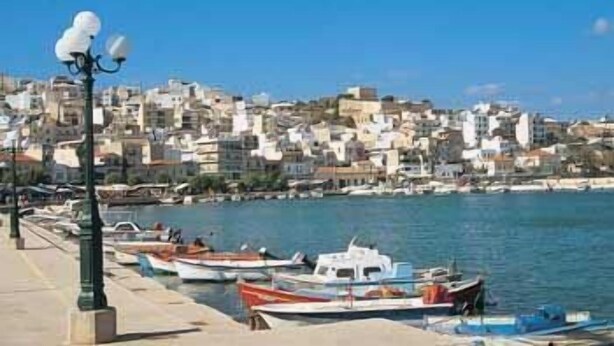 A coastal town with a marina filled with boats, a clear blue sky, and buildings along the waterfront. - Hotel Krystal (Sitia)