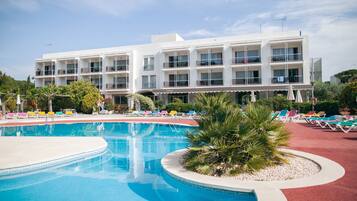 Un hotel con piscina, varios balcones y sillas de descanso coloridas.