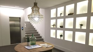 Un interior moderno con una escalera, una mesa con una botella y una planta, y una pared con paneles iluminados.