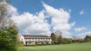 A large, multi-story building with a symmetrical facade, surrounded by a well-maintained lawn and trees. - Das Seela Braunschweig (Braunschweig)