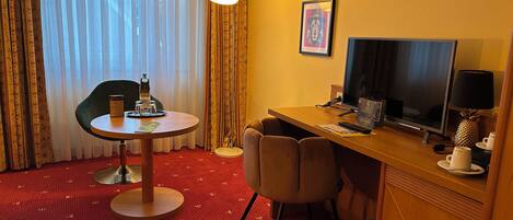 Una habitación de hotel con una mesa redonda, un escritorio con una computadora, una silla y una cama.