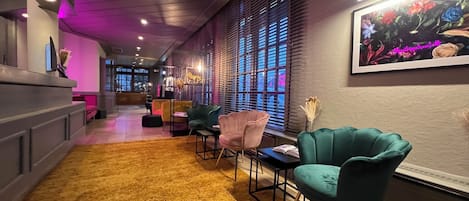 Un espacio lounge moderno con una alfombra de pelo amarillo, sillones azul aguamarina y un ventanal con persianas.