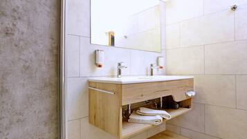 Un baño moderno con un tocador de madera, un espejo grande y un perchero para toallas.