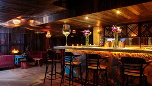 A bar area with wooden bar counter, bar stools, and decorative vases. - Gen Rooms (Santiago)