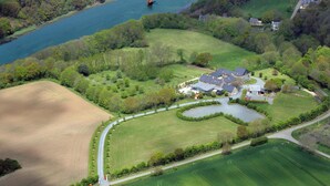 Vista aérea de una extensa propiedad con una casa principal, un lago y campos circundantes.