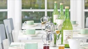 A dining area with tables set for tea service, featuring green tea bottles and teapots.