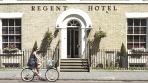 A Regency Hotel with a classic brick facade, a central entrance with a white arch, and a gated driveway.