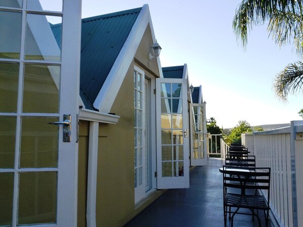 A corridor with multiple rooms, each with a door and windows. - Yamkela Guest House (Oudtshoorn)