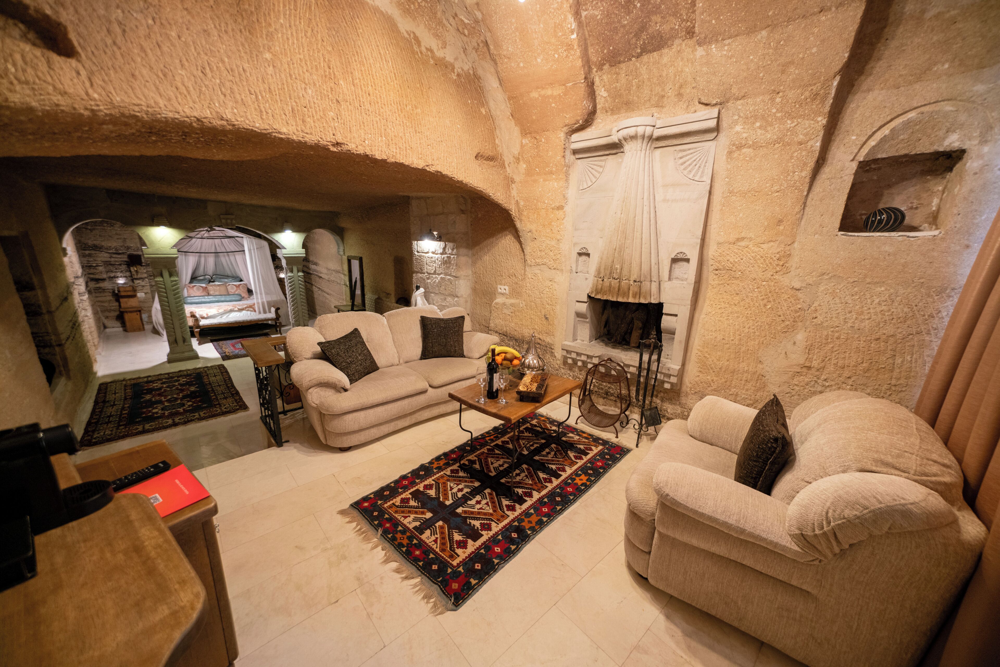 A cozy living room with a sofa, armchair, and coffee table, featuring a patterned rug and a decorative vase.