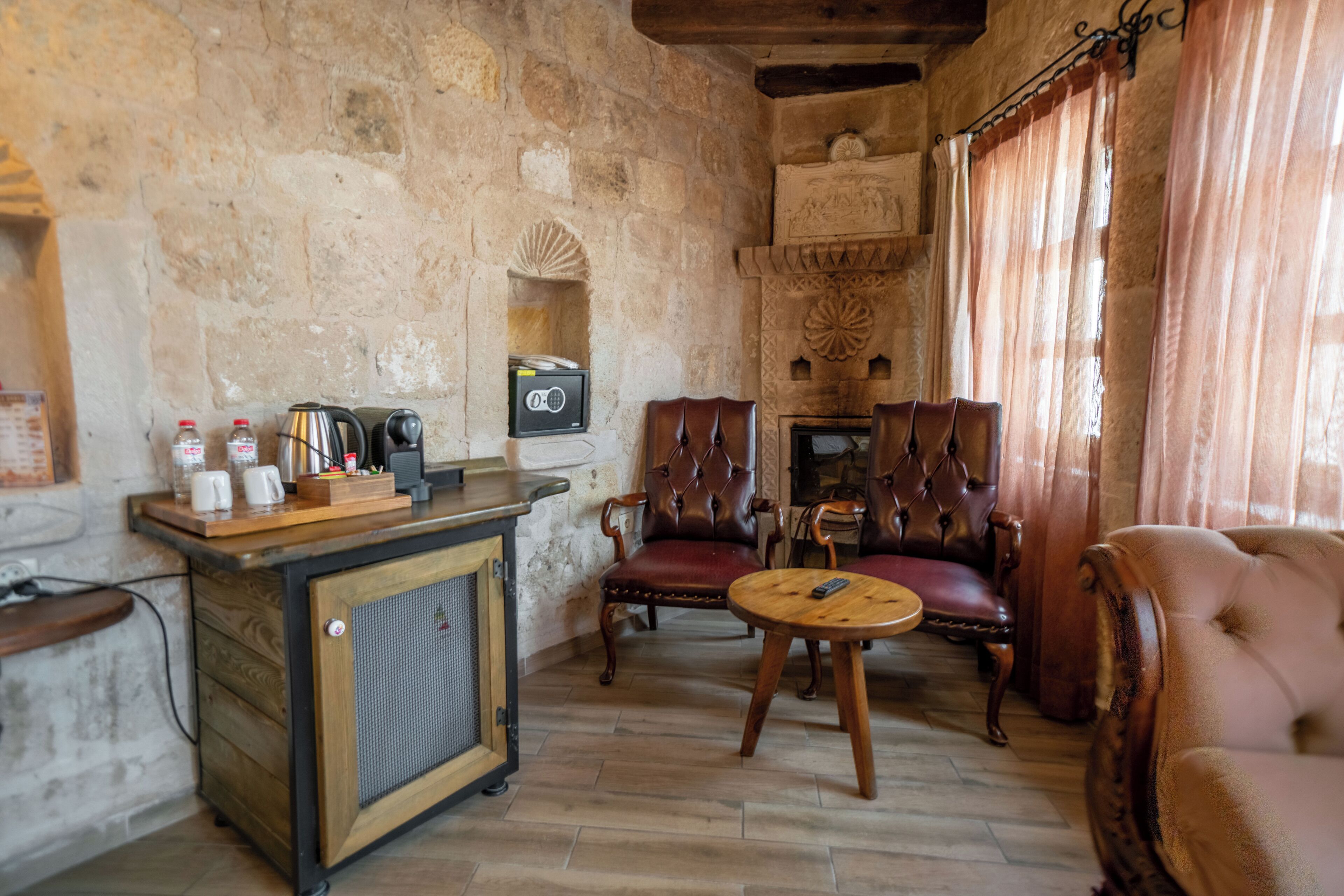 Una habitación de paredes de piedra con una zona de bar, sillones de cuero y una mesa redonda.