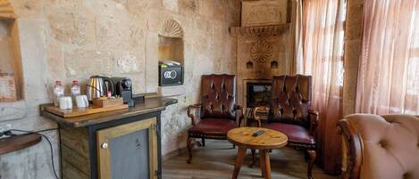 A stone-walled room with a bar area, leather chairs, and a round table.