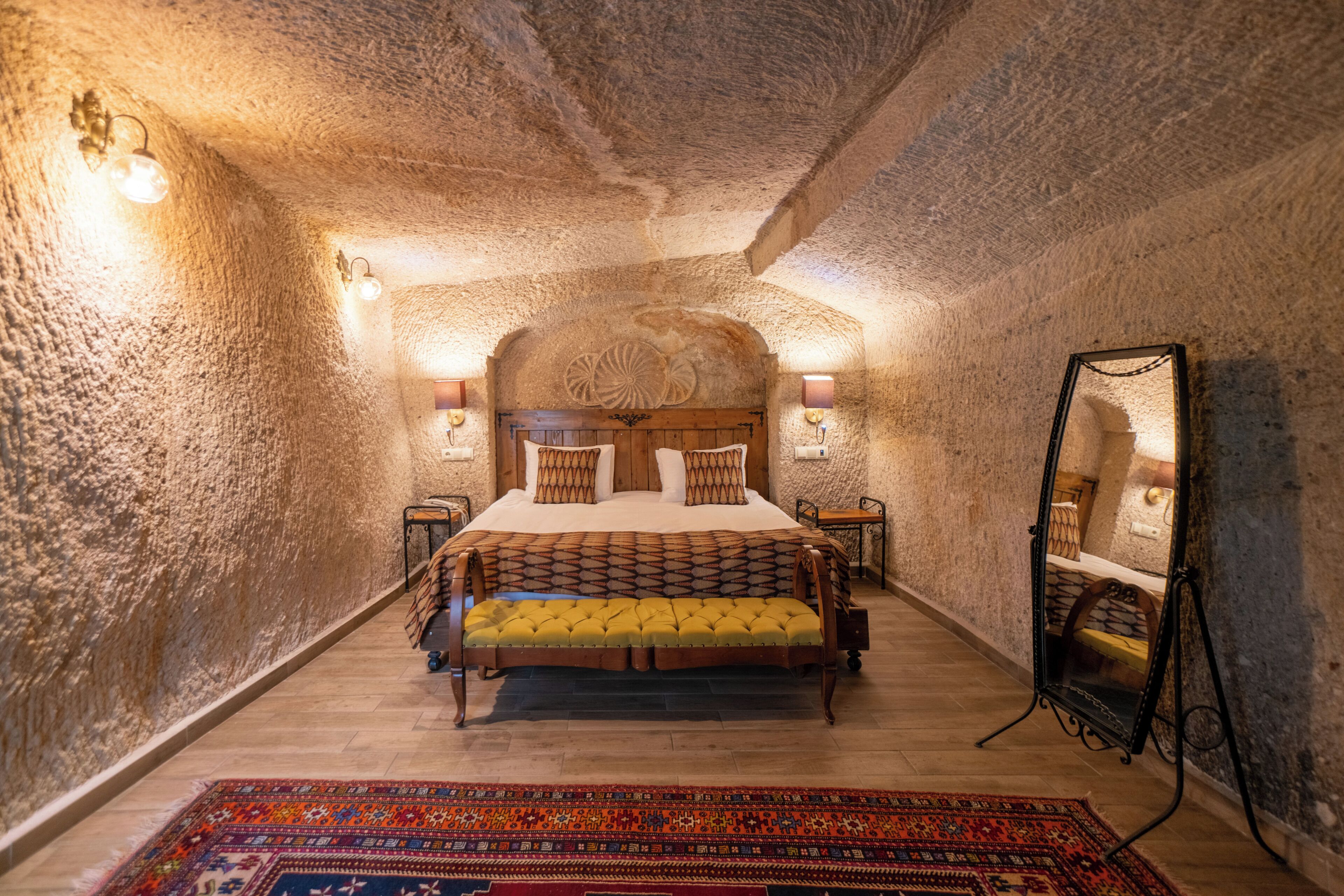 A bedroom with a bed, a mirror, and a rug.
