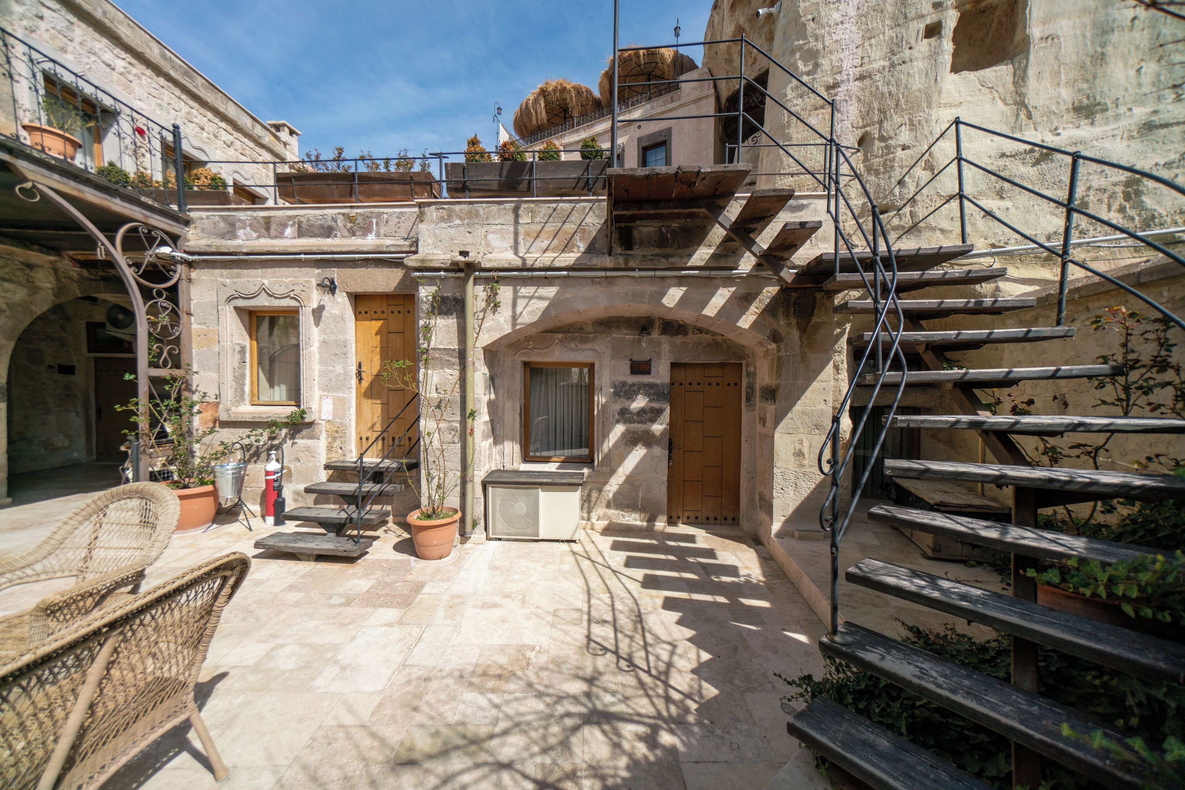 A courtyard with stone steps, a wooden door, and a metal staircase.